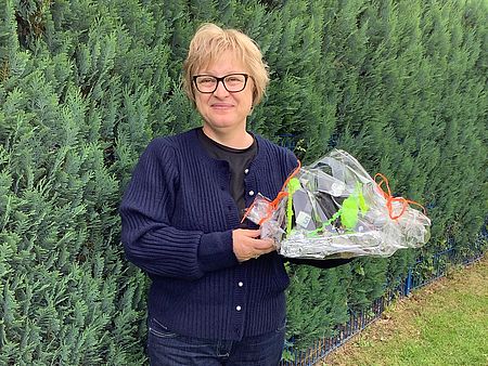Erzieherin Svetlana Vogel im DRK-Heilpädagogischen Kindergarten mit einem Blumenstrauß in der Hand, im Grünen, lächelt in die Kamera