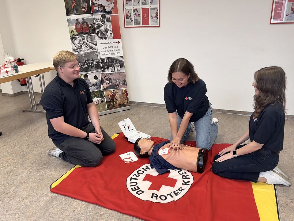2026_08_18_FSJ_EH_Verabschiedung_Lars_Begrüßung_Finia__Lena_Sophie_16_.jpeg Verabschiedung und Begrüßung im DRK-Kreisverband Göttingen-Northeim e. V.: alte und neue FSJler in Bereich Erste-Hilfe demonstrieren Erste-Hilfe mit Übungspuppe auf einer DRK-Decke
